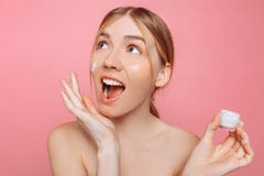 震惊女孩在她的手上拿着润肤霜并且应用它于她的面孔润湿皮肤和去除皱痕 免版税库存照片 震惊女孩在她的手上拿着润肤霜并且应用它于她的面孔润湿皮肤和去除皱痕 免版税库存照片